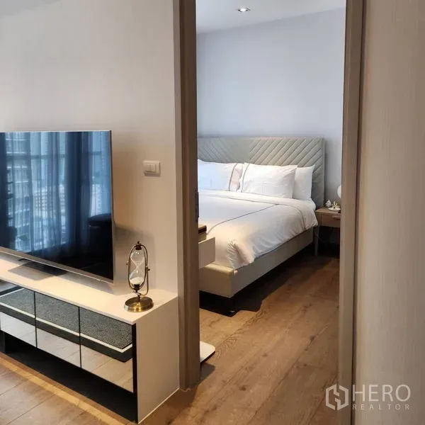 Condominium for rent - View from living area into a bedroom with upholstered bed and a TV console in the hallway.
