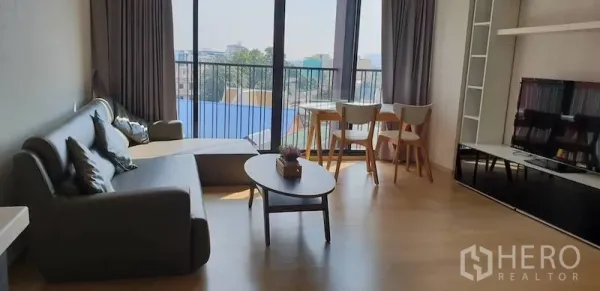 公寓 出租在Watthana, Bangkok - 开放式客餐厅，设沙发、茶几、电视柜与落地窗，可眺望城市景观。