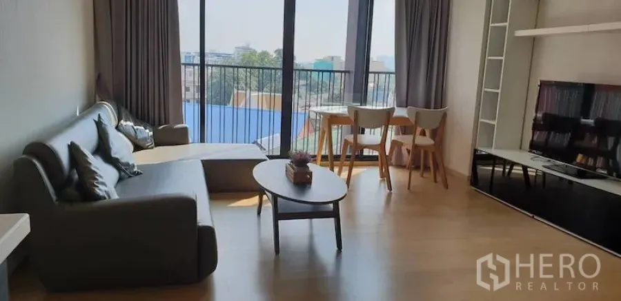 公寓 出租在Watthana, Bangkok - 开放式客餐厅，设沙发、茶几、电视柜与落地窗，可眺望城市景观。