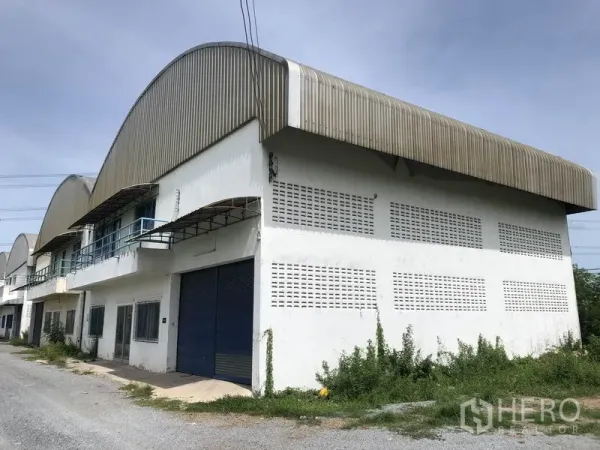 คลังสินค้า ให้เช่าในNonthaburi - ด้านหน้าโกดังยูนิตริม หลังคาโค้ง ประตูม้วนสีน้ำเงิน เขตไทรน้อย นนทบุรี