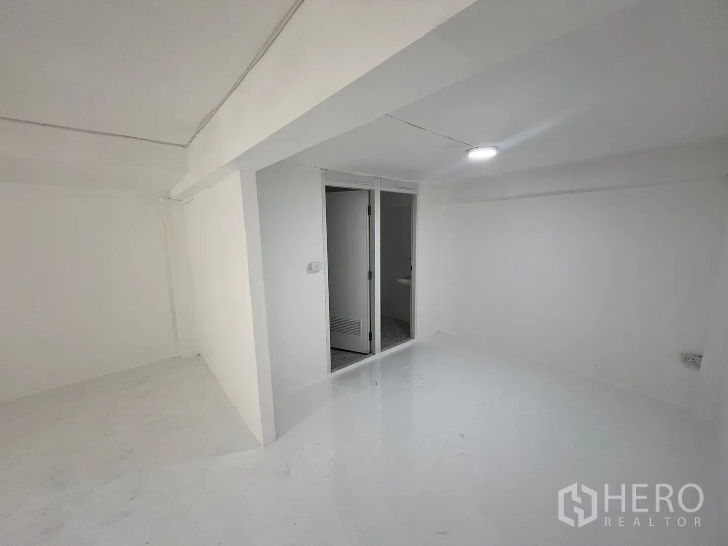 Retail Space for rent in Khlong Toei, Bangkok - Compact rear area with sliding glass door to restrooms, white walls and ceiling light.
