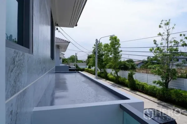 独立式住宅 出售在Lat Krabang, Bangkok - 狭长阳台俯瞰宁静的林荫小街与社区人行道