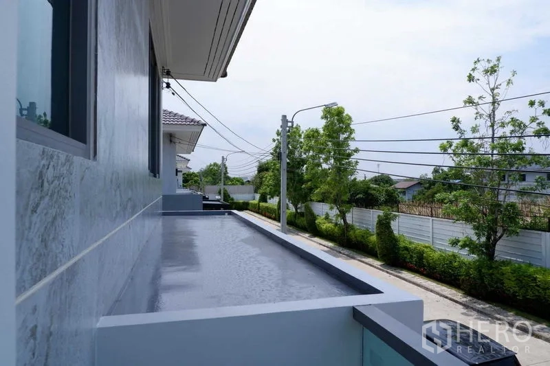 独立式住宅 出售在Lat Krabang, Bangkok - 狭长阳台俯瞰宁静的林荫小街与社区人行道