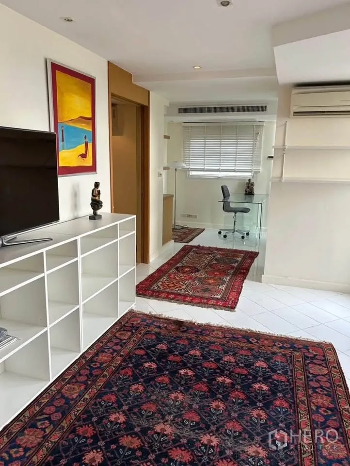 公寓 出租或出售在Yan Nawa, Bangkok - 起居区带白色收纳格、彩色装饰画与玻璃书桌。