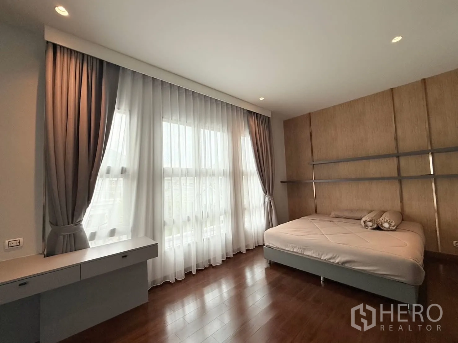 独立式住宅 出租或出售在Bang Phli, Samut Prakan - 卧室采光充足，落地窗、纱帘、软包床头与木地板。