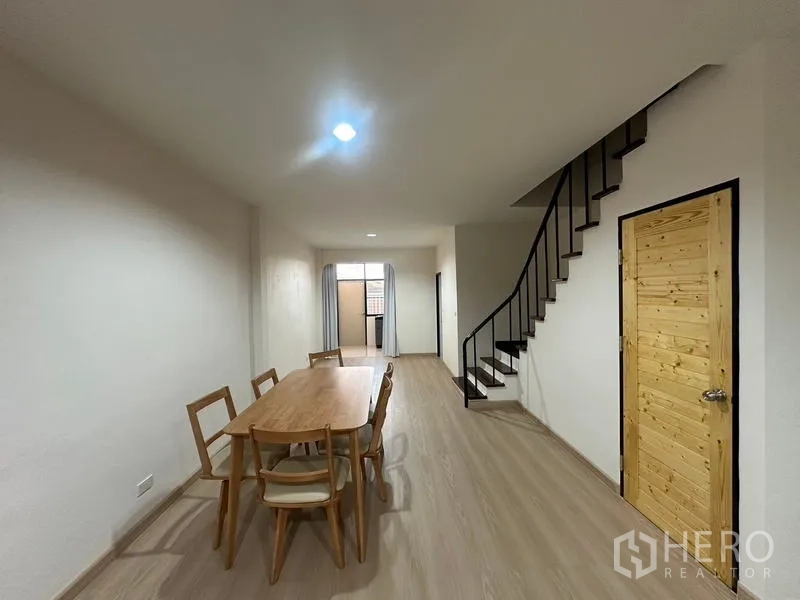 Townhouse for rent or sale in Phra Khanong, Bangkok - Dining zone with wooden table for six beside the staircase.