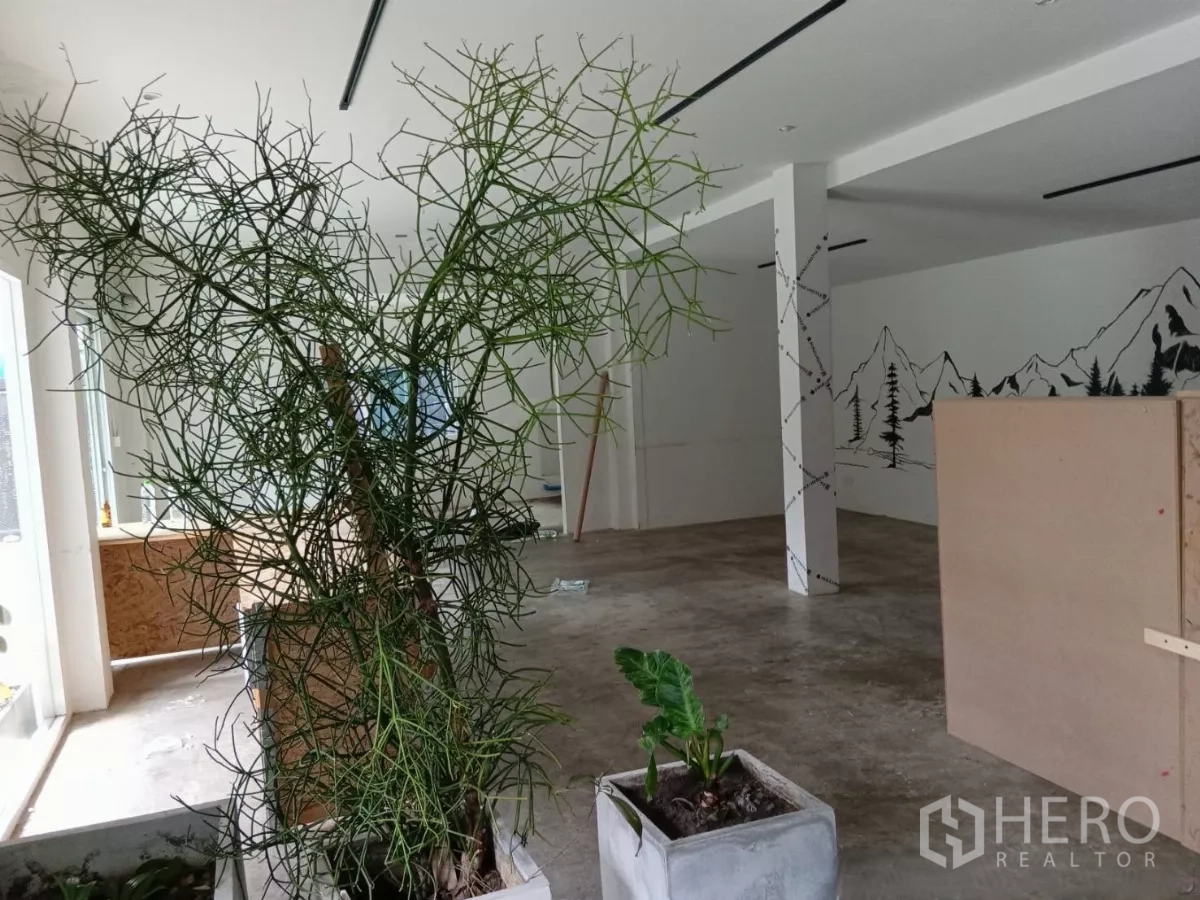 零售空间 出租在Huai Khwang, Bangkok - 开放式零售大厅，混凝土地面、绿植与山景壁画。