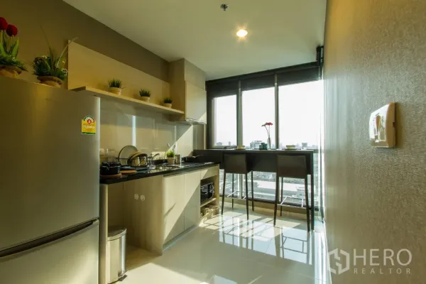 Condominium for rent or sale in Sathon, Bangkok - Modern kitchen with light-wood cabinetry, black countertop, stainless fridge and a city-view breakfast bar by wide windows.