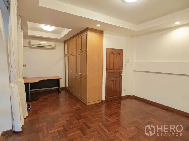 联排别墅 出租在Khlong Toei, Bangkok - 明亮卧室，超大木质衣柜与筒灯照明。