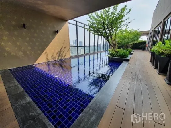 公寓 出售在Ratchathewi, Bangkok - 屋顶泳池，蓝色马赛克池面，木质平台与绿植，远眺城市天际线。