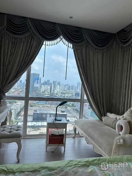Condominium for sale in Huai Khwang, Bangkok - Floor-to-ceiling window with draped curtains showcasing a Bangkok city view.
