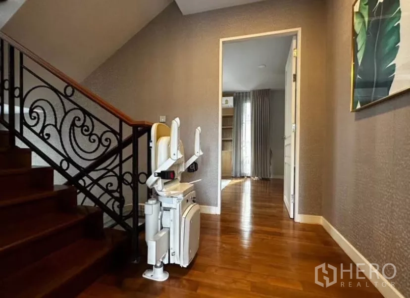 Townhouse for rent in Yan Nawa, Bangkok - Staircase with wrought-iron railing and an integrated stairlift on polished wooden steps.