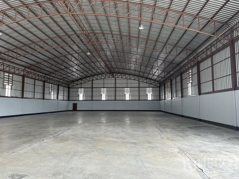 Factory for rent or sale in Sai Noi, Nonthaburi - Rear wall view of the warehouse highlighting ventilation windows and clear, open workspace.