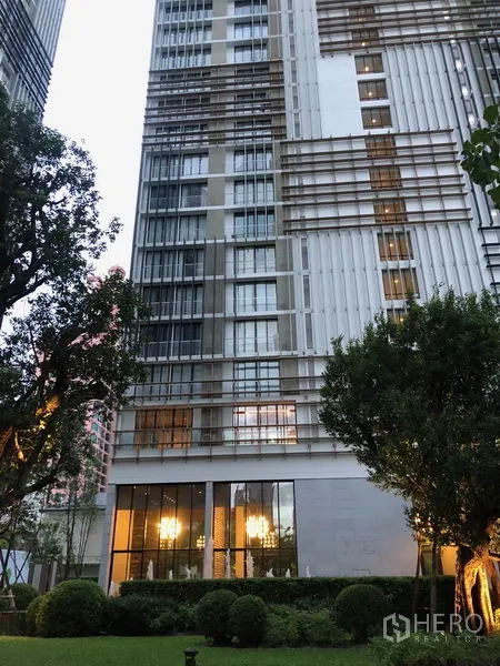 Condominium for rent in Khlong Toei, Bangkok - Modern high-rise condominium exterior with landscaped garden at the base.
