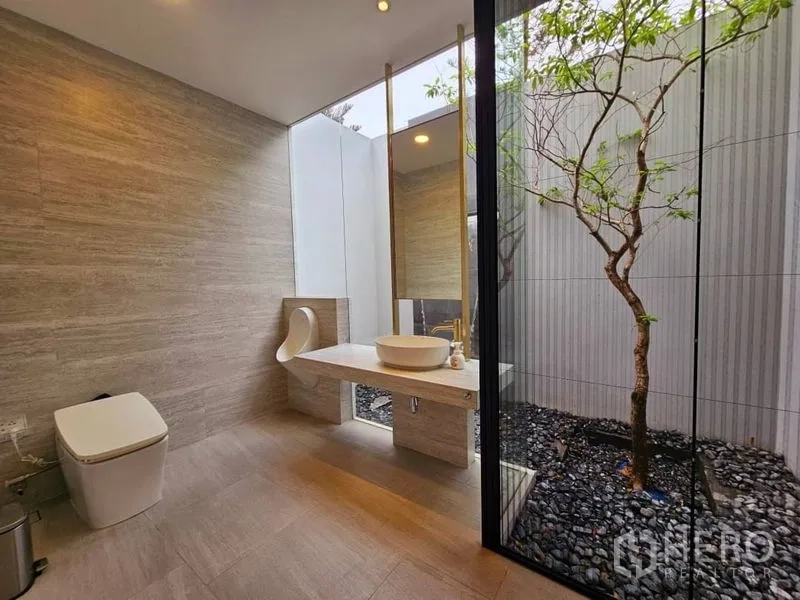 Detached House for rent or sale in Saphan Sung, Bangkok - Modern bathroom with floor-to-ceiling glass opening to a private courtyard with a tree.