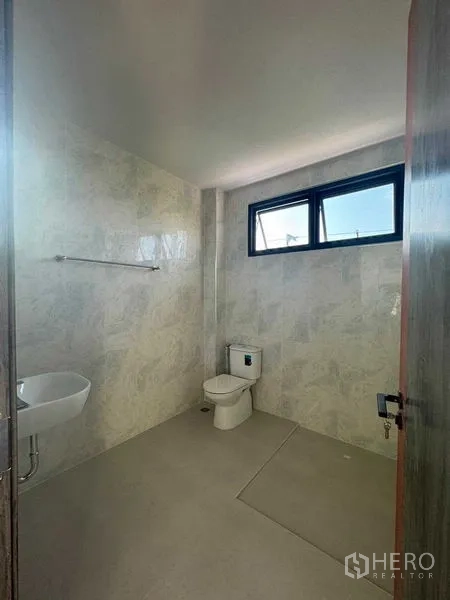 Home Office for rent in Don Mueang, Bangkok - Bright bathroom with window, toilet, small basin and walk-in shower area.