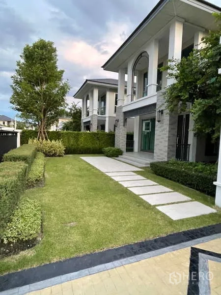 Detached House for rent or sale in Lat Krabang, Bangkok - Front garden with a neat lawn, stepping-stone path and trimmed hedges by the facade.