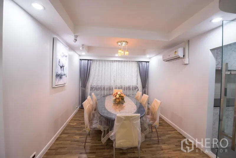 Condominium for rent in Khlong Toei, Bangkok - Formal dining room with oval table, chandelier lighting, curtains and air conditioning.