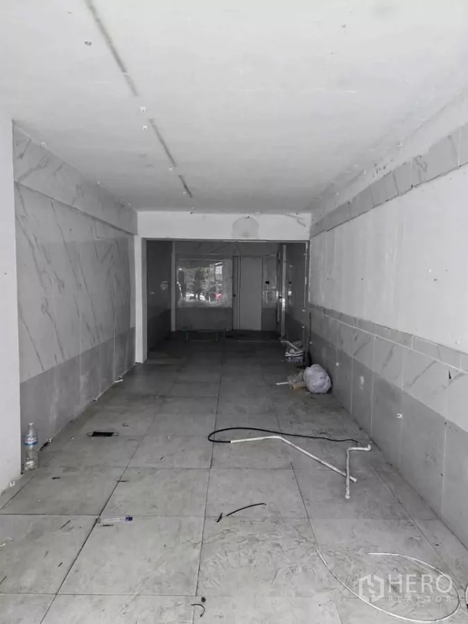Retail Space for rent in Watthana, Bangkok - Empty long and narrow retail interior with tiled floor, white walls and exposed wiring ready for fit-out.
