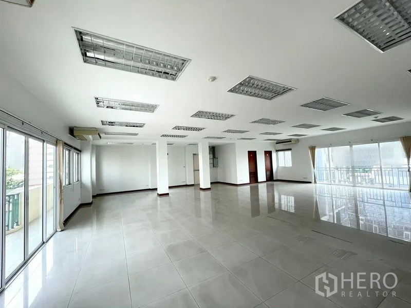 Office Space for rent in Bang Rak, Bangkok - Spacious open‑plan office floor with tiled flooring, columns, grid ceiling lights and balcony windows.