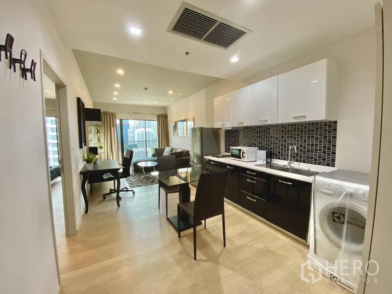 Condominium for rent in Bangkok - Open kitchen with mosaic backsplash, dining table and laundry area leading to the living space.
