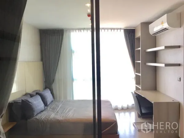 Condominium for rent in Watthana, Bangkok - Bright bedroom with a queen bed, desk, built-in shelves and blackout curtains.