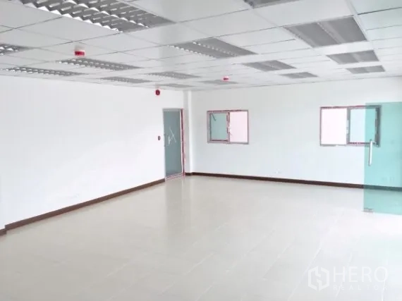 Factory for rent in Bang Sao Thong, Samut Prakan - Bright internal office room with drop ceiling, tiled floors and glass doors.