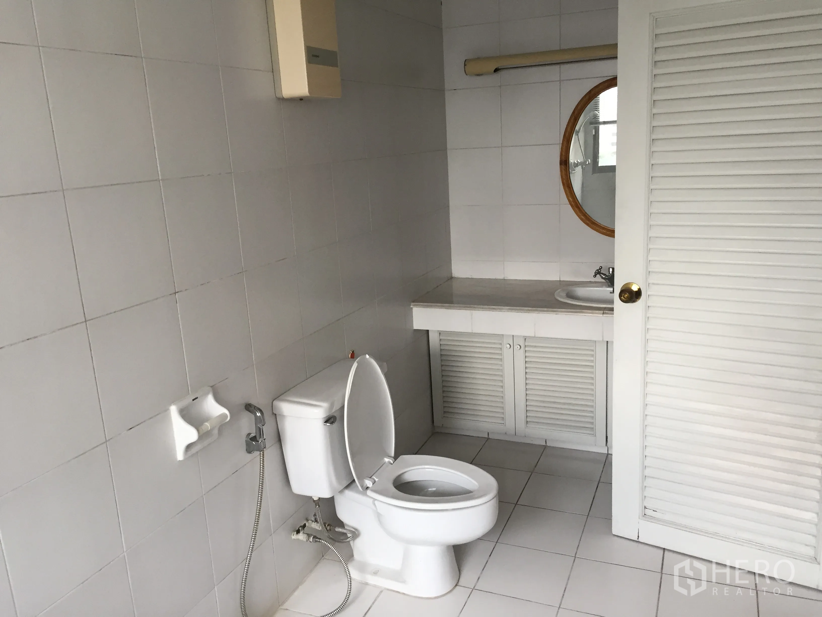 公寓 出租在Watthana, Bangkok - 白色瓷砖浴室，带坐便器与圆镜洗手台