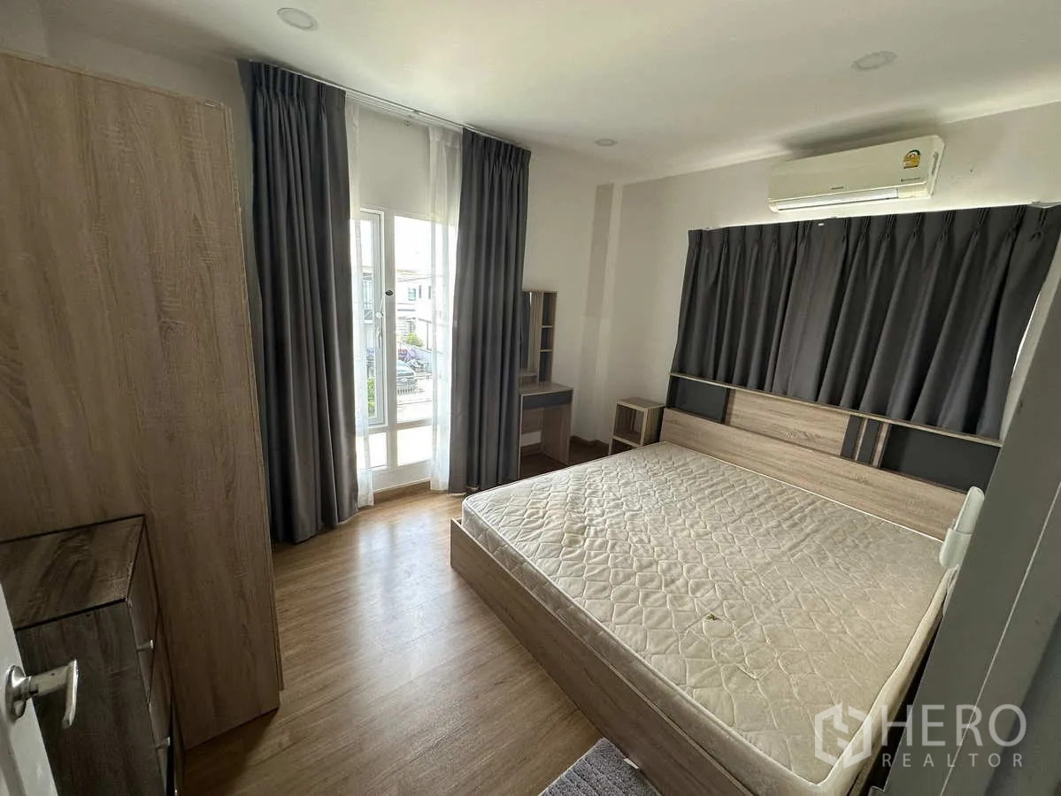 Detached House for rent in Khlong Luang, Pathum Thani - Furnished bedroom with bed, wardrobe and access to the balcony.