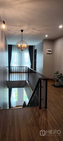 Townhouse for rent or sale in Saphan Sung, Bangkok - Stair landing with pendant light and metal railing in a modern townhouse.
