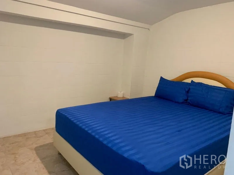 Shophouse for rent in Khlong Toei, Bangkok - Simple bedroom with a king-size bed and blue linens.