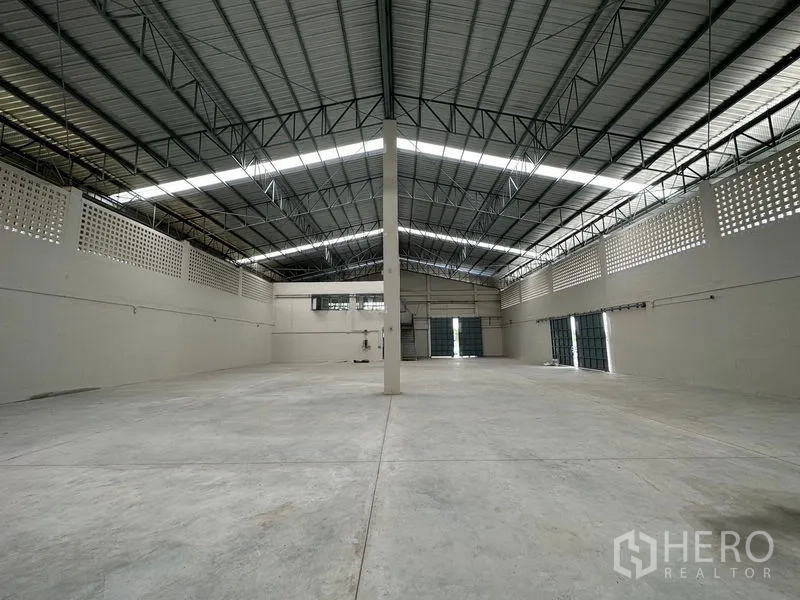 工厂 出租在Lam Luk Ka, Pathum Thani - 开阔仓库分区，中央立柱与多樘卷帘门。