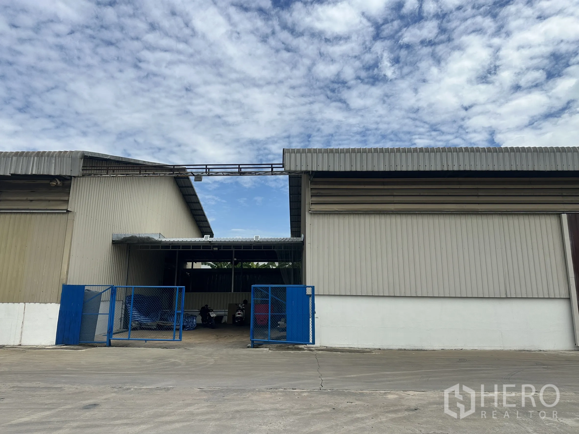 工厂 for rent in Lat Krabang, Bangkok - 蓝色大门的服务入口位于两栋金属板建筑之间。