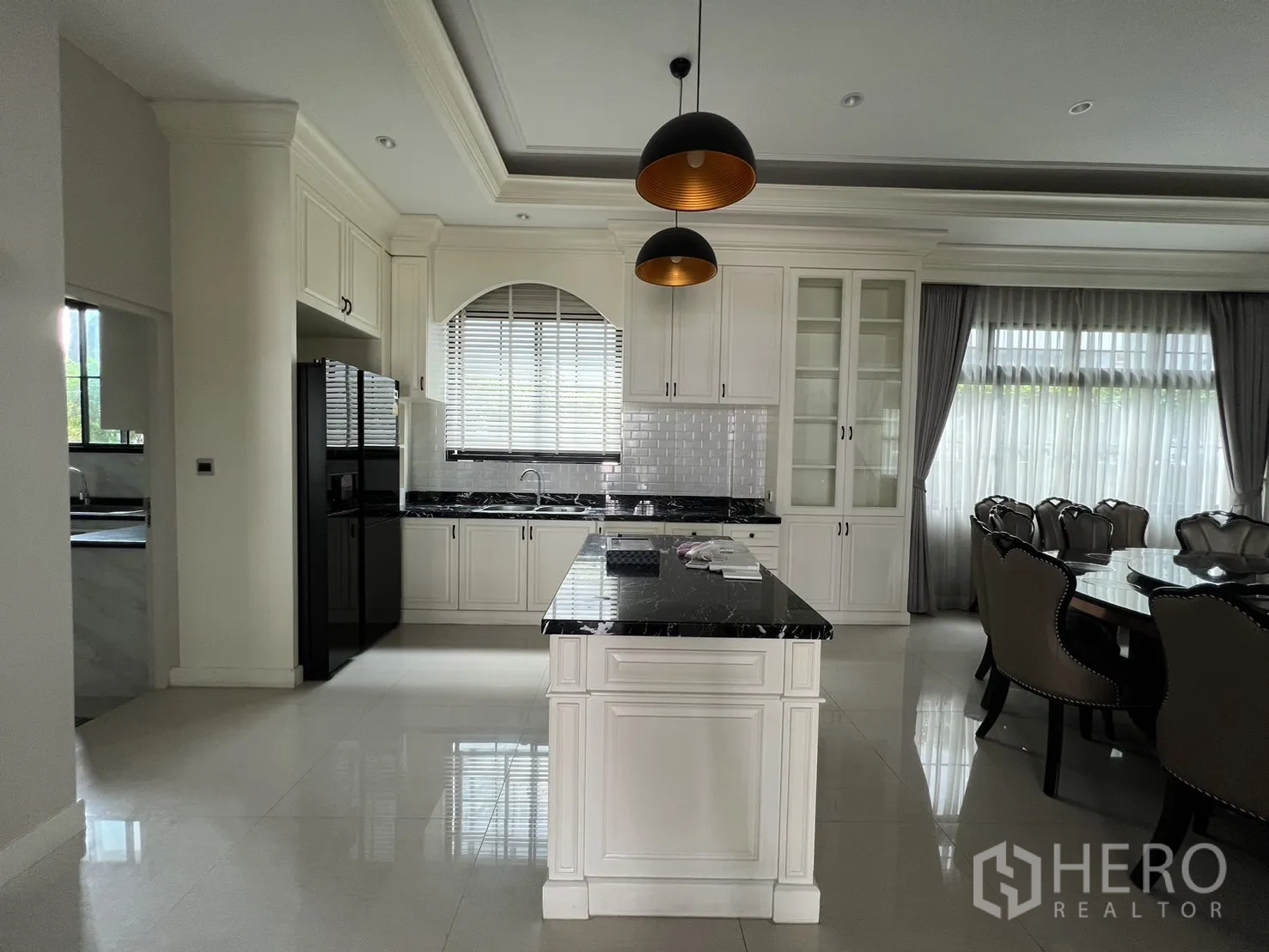 Detached House for rent or sale in Prawet, Bangkok - Western kitchen with black-stone island, white cabinetry and pendant lamps.