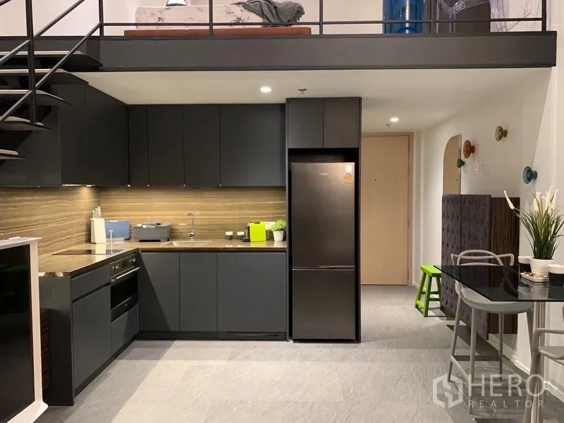 Condominium for rent in Bang Rak, Bangkok - Close-up of modern L-shaped kitchen with built-in oven, cooktop and fridge.