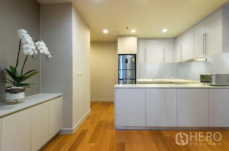 Condominium for rent in Bang Kho Laem, Bangkok - Bright kitchen with peninsula counter, white cabinets and stainless steel refrigerator.