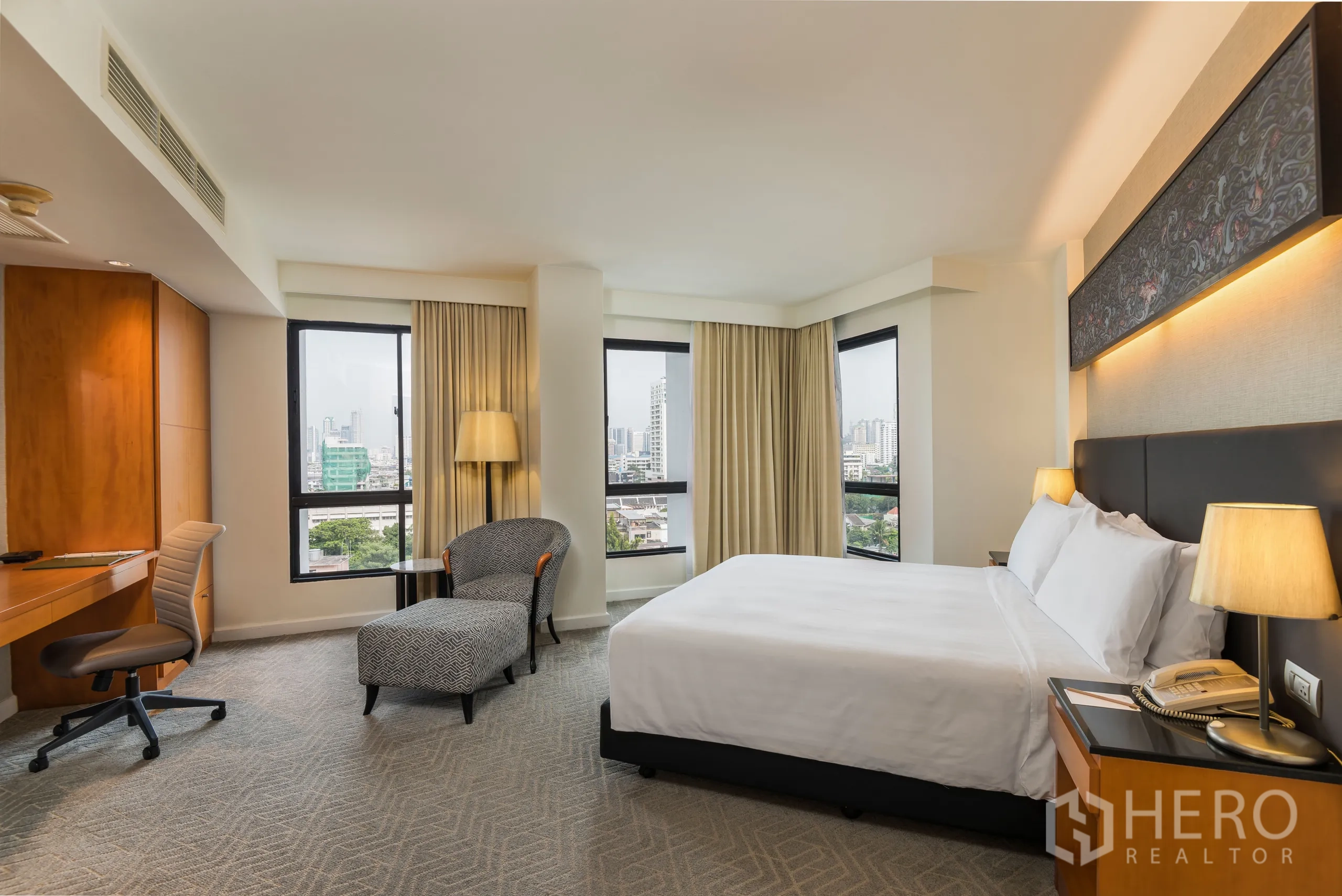 公寓 出租在Yan Nawa, Bangkok - 转角主卧，书桌与贵妃椅，多扇窗框出城市景色。