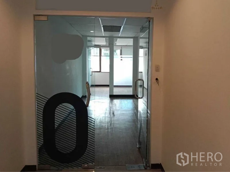办公空间 出租在Watthana, Bangkok - 玻璃双开门入口，通向采光良好的办公区与窗户、立柱。