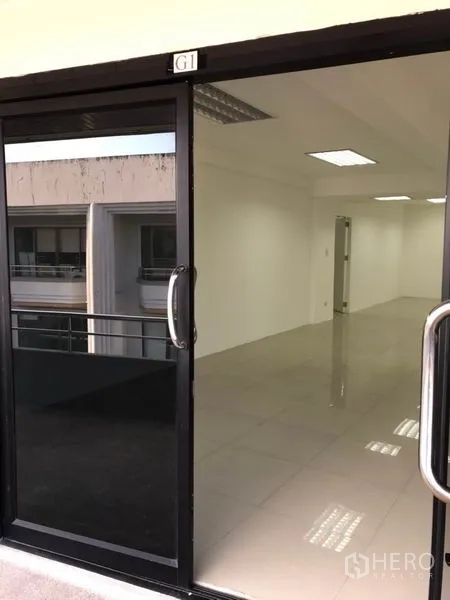 办公空间 出租在Watthana, Bangkok - 走廊外透过玻璃门看到明亮整洁的办公室内部。