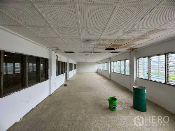 Factory for rent in Sai Noi, Nonthaburi - Empty office corridor with louvered windows on both sides, tiled ceiling and concrete floor.