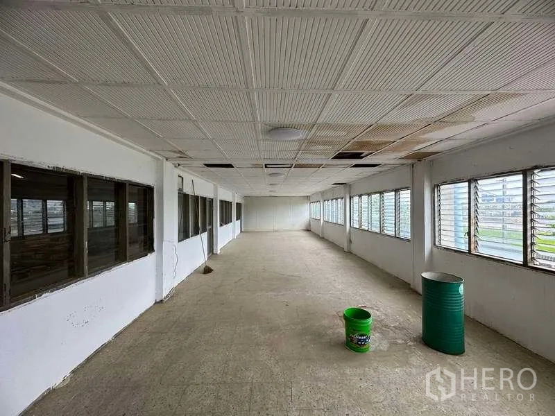 Factory for rent in Sai Noi, Nonthaburi - Empty office corridor with louvered windows on both sides, tiled ceiling and concrete floor.