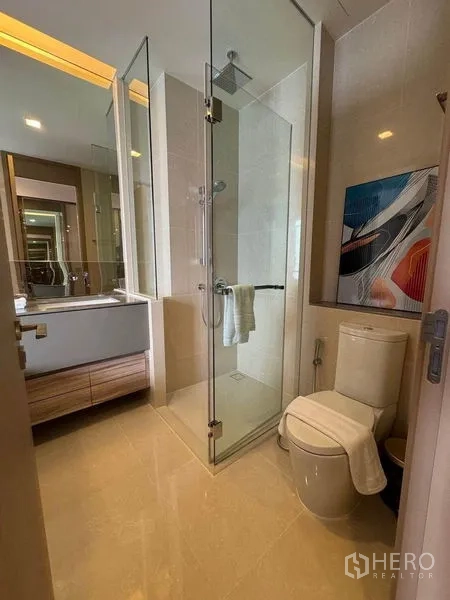 公寓 出租在Watthana, Bangkok - 现代浴室，玻璃淋浴间、座厕与镜柜洗手台。