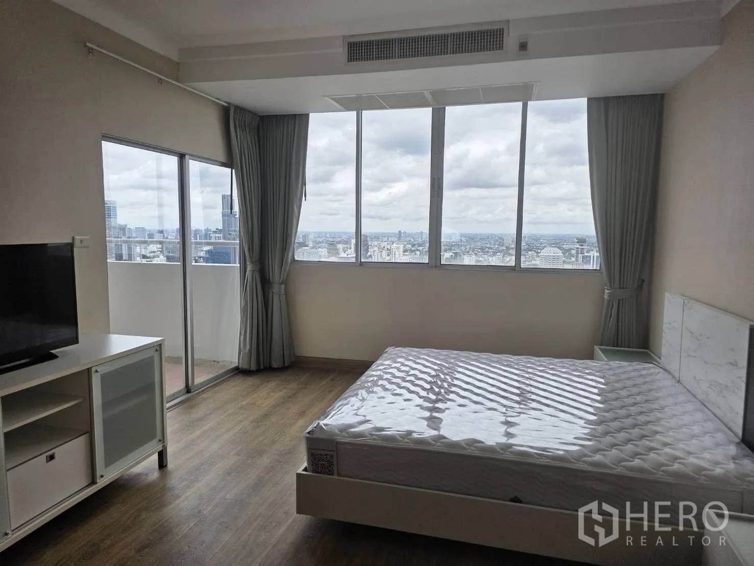 Condominium for rent in Khlong Toei, Bangkok - Master bedroom with balcony access and skyline backdrop.