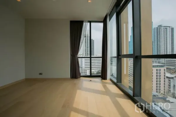 Condominium for rent or sale in Watthana, Bangkok - Bright corner room with floor-to-ceiling windows, light wood floors and panoramic city view.