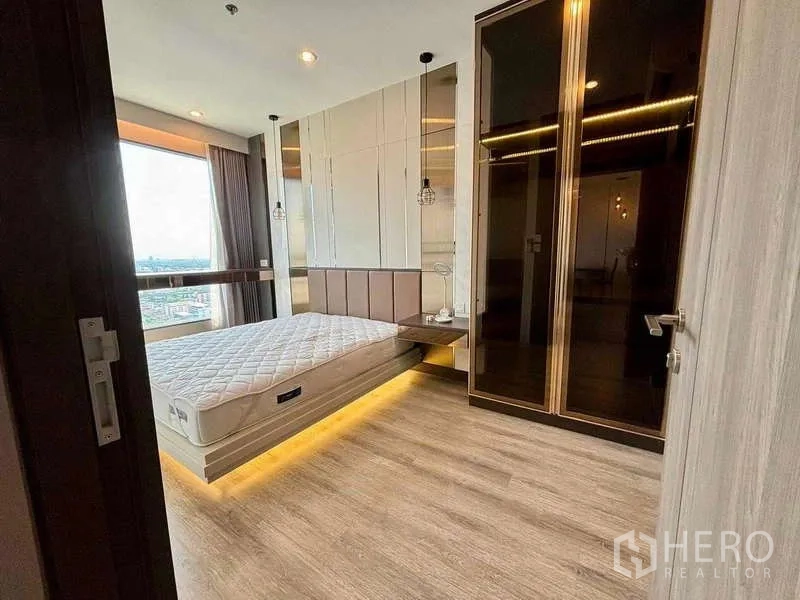 Condominium for rent or sale in Bang Na, Bangkok - Master bedroom with platform bed, warm under-bed LED lighting and a large glass wardrobe.