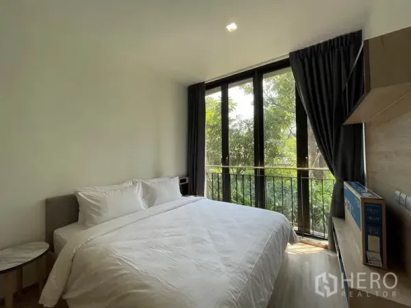 Condominium for sale in Watthana, Bangkok - Cozy bedroom with floor-to-ceiling windows and garden outlook.