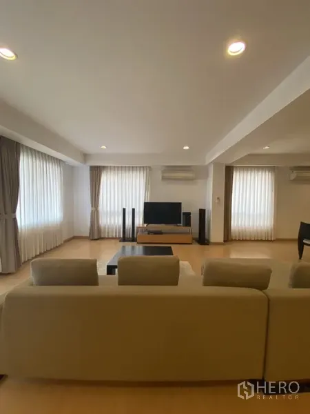 房间 出租在Watthana, Bangkok - 明亮客厅，多面窗配薄纱窗帘，沙发正对电视。
