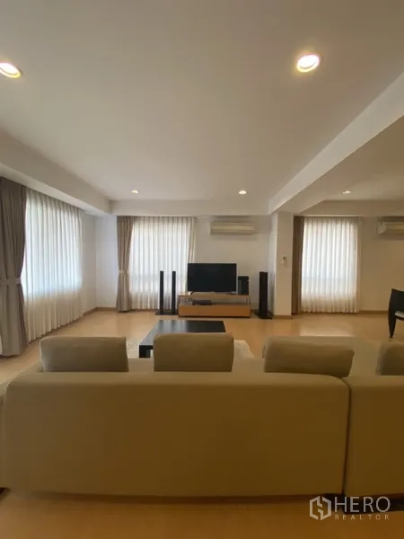 房间 出租在Watthana, Bangkok - 明亮客厅，多面窗配薄纱窗帘，沙发正对电视。