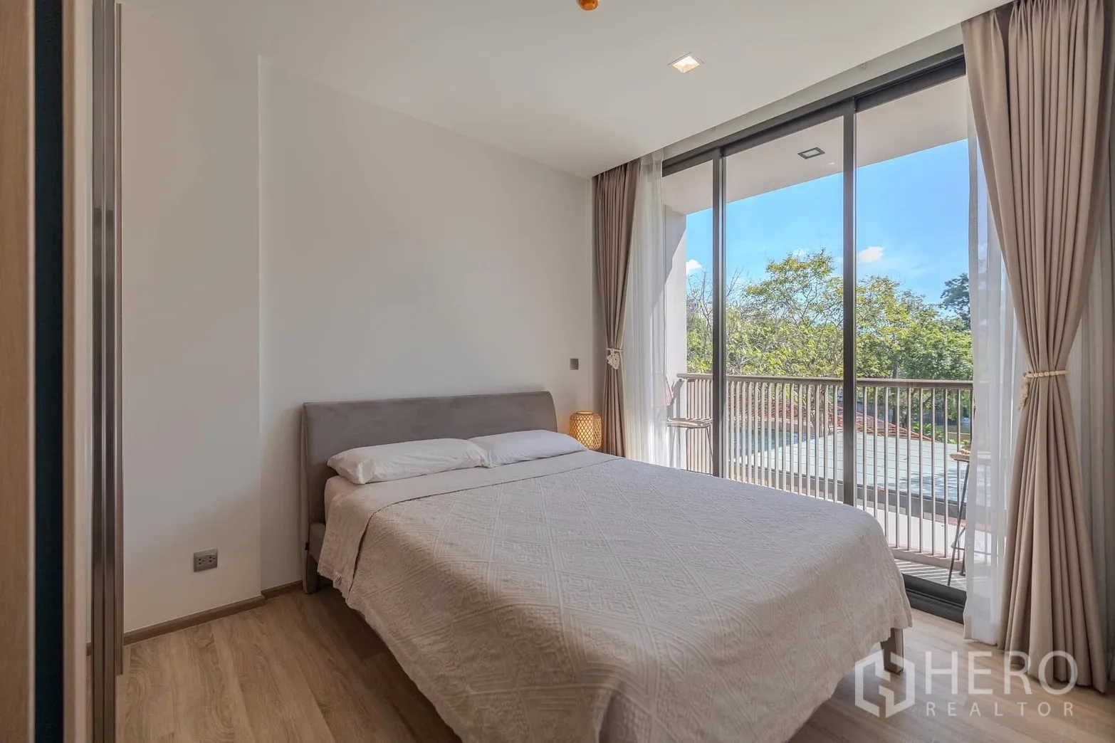 คอนโด for rent in Watthana, Bangkok - ห้องนอนสว่าง เตียงคู่ ประตูบานเลื่อนสูงจรดเพดาน เปิดสู่ระเบียงวิวต้นไม้และสระ