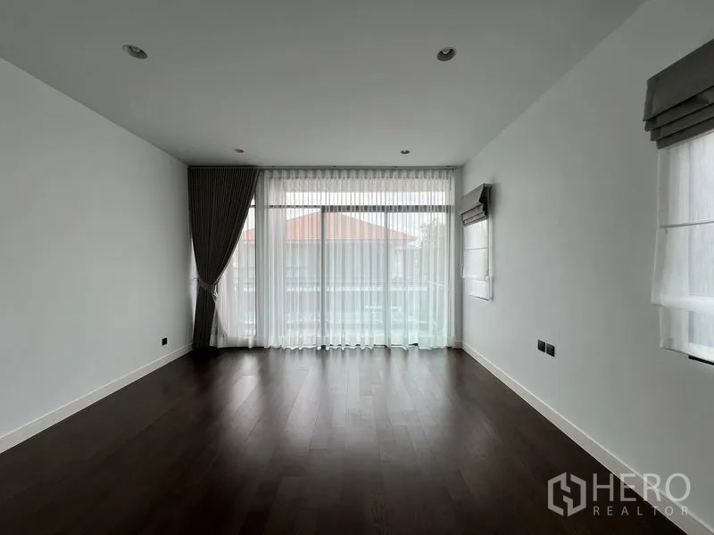Detached House for rent in Bang Kapi, Bangkok - Large bedroom with floor-to-ceiling windows, sheer curtains and balcony access.